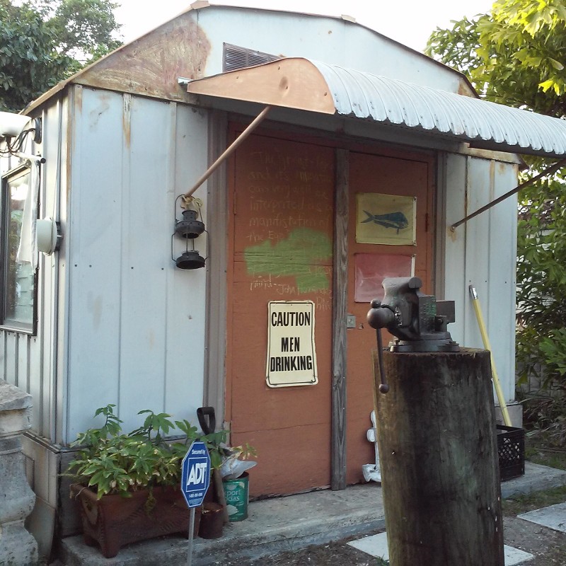 A Quirky, Weathered Shed With A "Caution Men Drinking" Sign